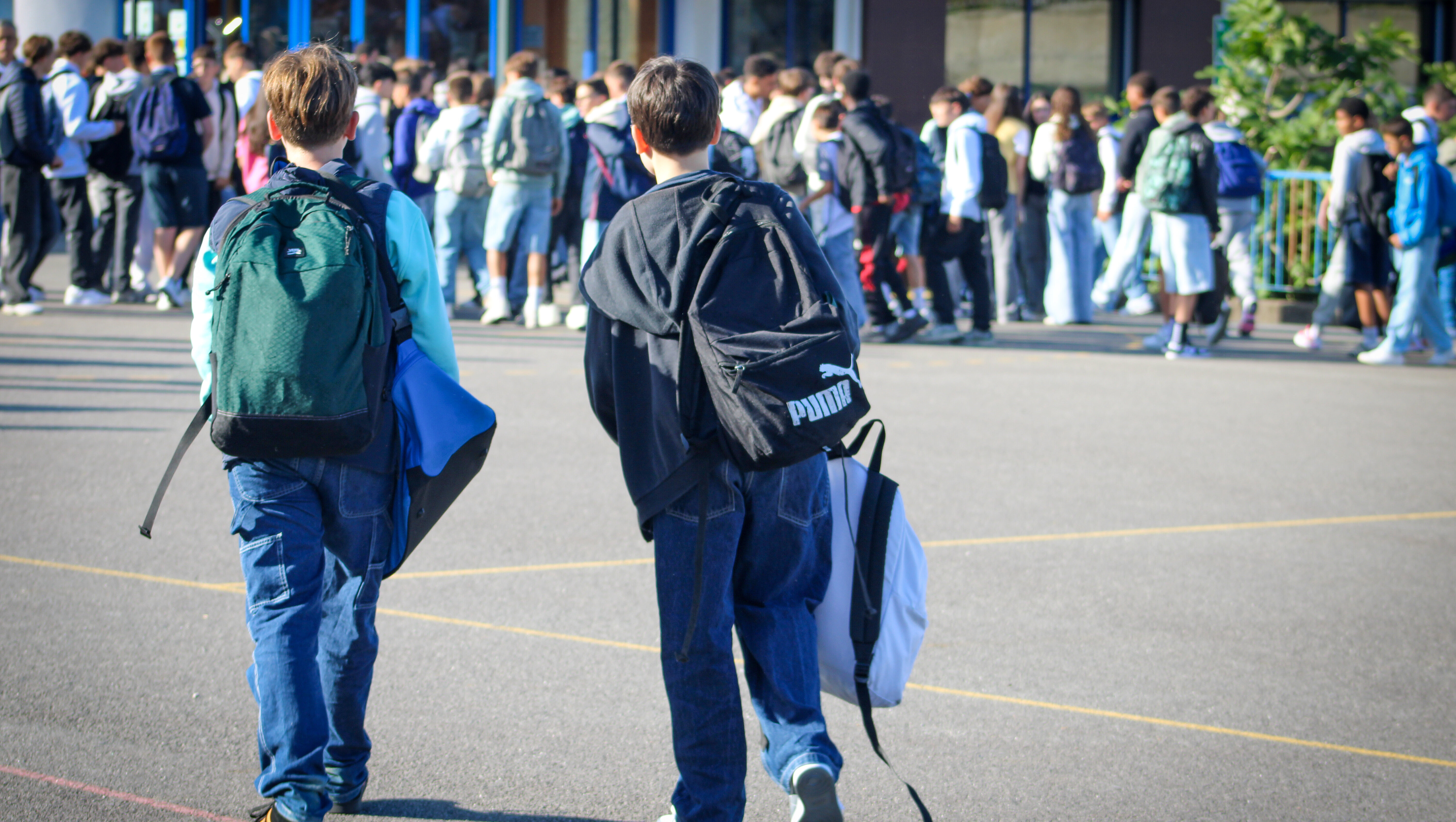Deux collégiens de dos dans la cour de récréation