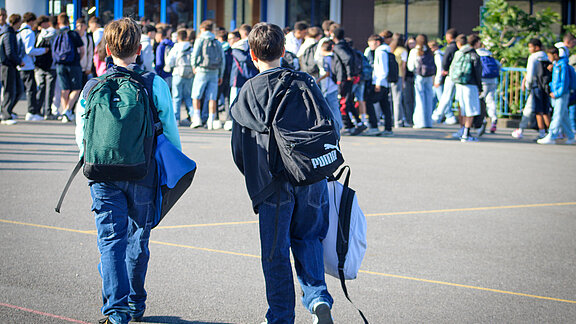 Rentrée-scolaire-2025 Deux collégiens de dos dans la cour de récréation