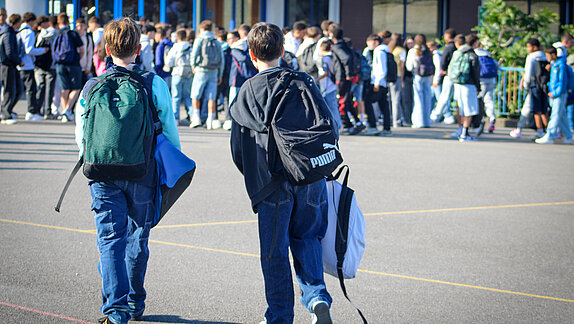 Deux collégiens de dos dans la cour de récréation