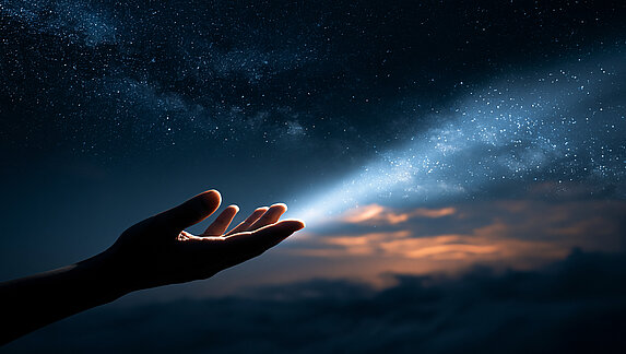 Glowing starlight beam streaming into an open human hand at night under a starry sky