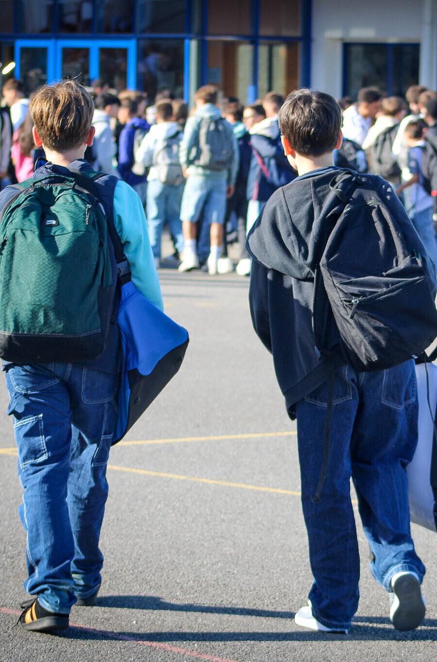 Deux collégiens de dos dans la cour de récréation