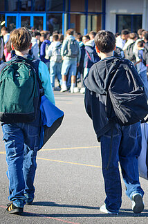 Deux collégiens de dos dans la cour de récréation