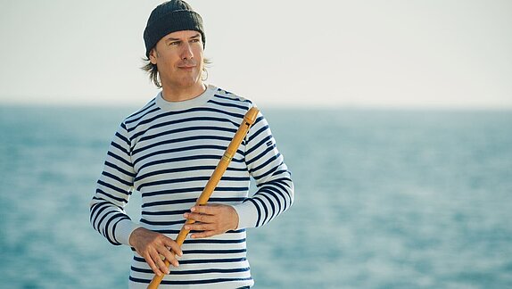 Homme en marinière tenant une flûte de musique