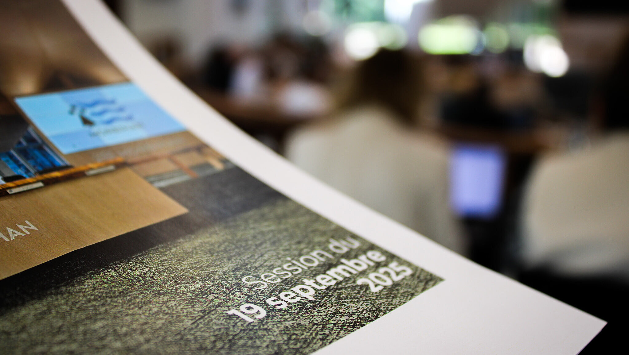 Dossier de presse en premier plan avec les élus dans l'hémicycle en second plan